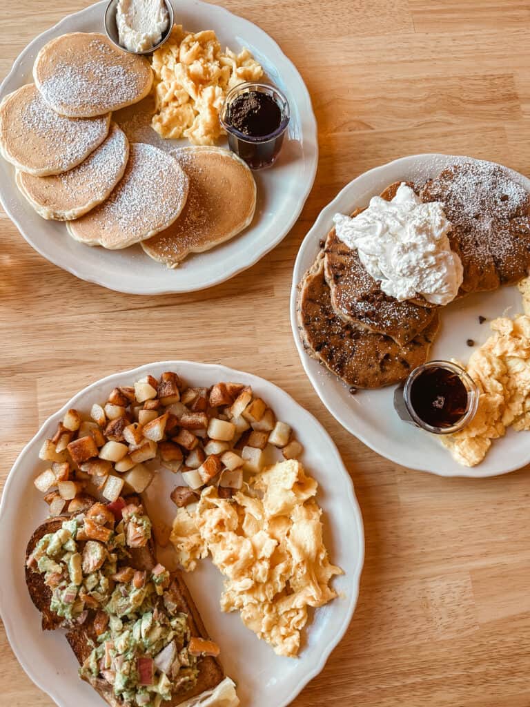 Variety of brunch items from The Original Pancake House in Spokane, Washington, including plain pancakes, chocolate chip pancakes, and avocado toast with eggs and potatoes.